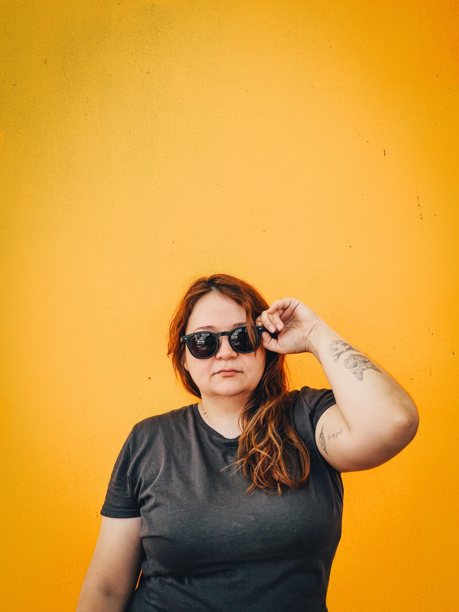 Karina Gil con lentes de sol frente a una pared amarilla